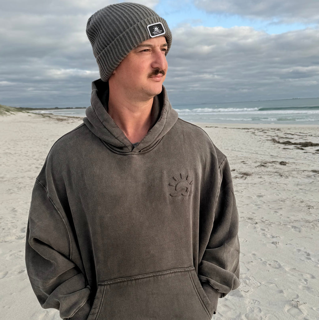 Man at beach wearing Aquaholics Charcoal Embossed Hoodie