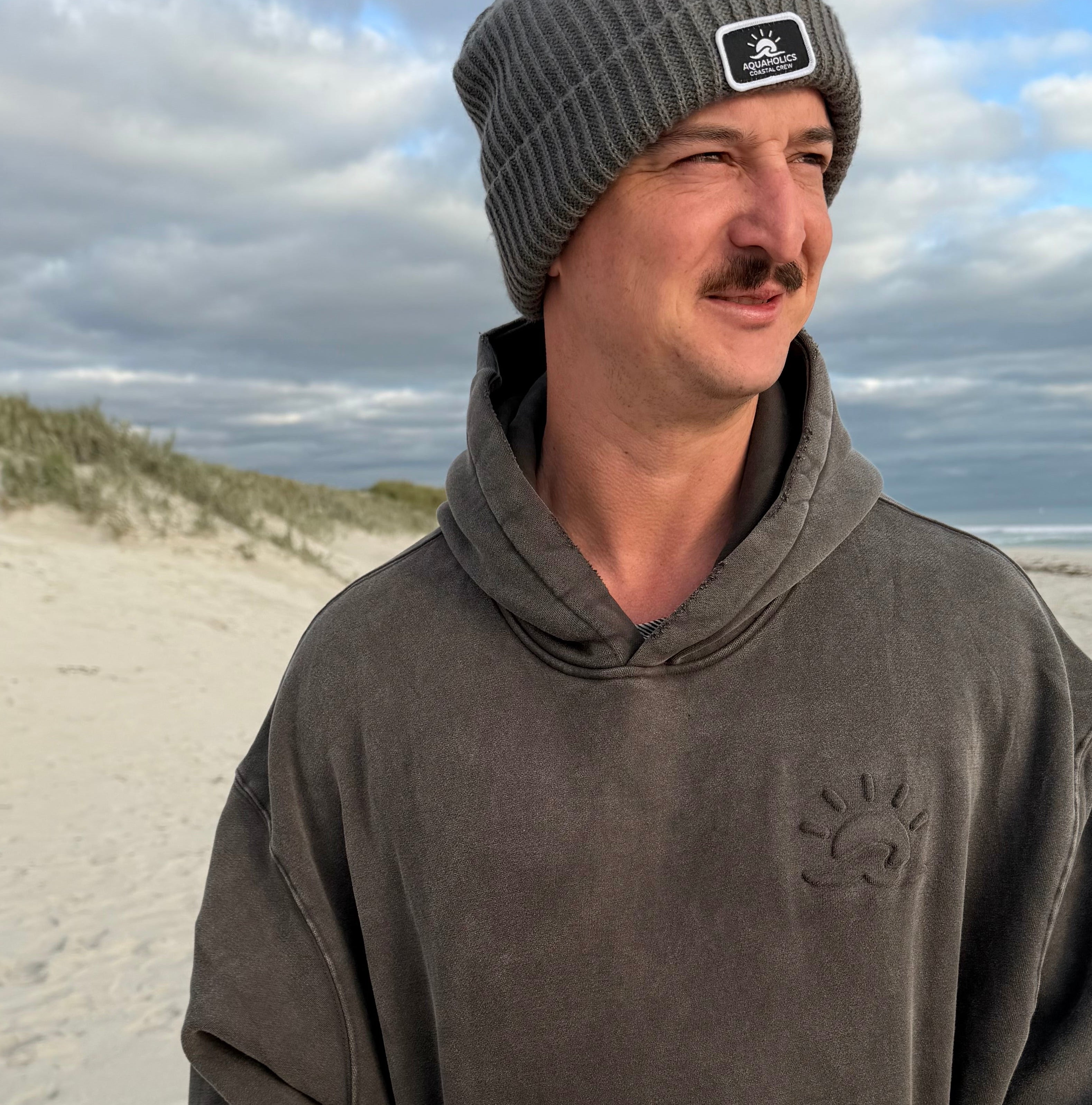 Man at beach wearing Aquaholics Anonymous hoodie