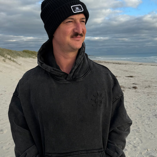 Man at beach wearing black Aquaholics Anonymous hoodie