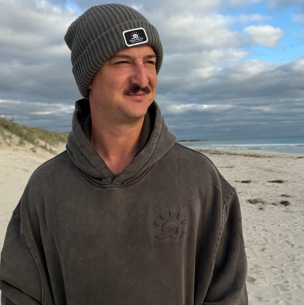 Man wearing Aquaholics Anonymous hoodie at beach