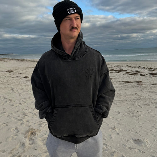 Man at beach wearing black hoodie 