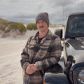 Man wearing Aquaholics beanie next to 4WD on the beach