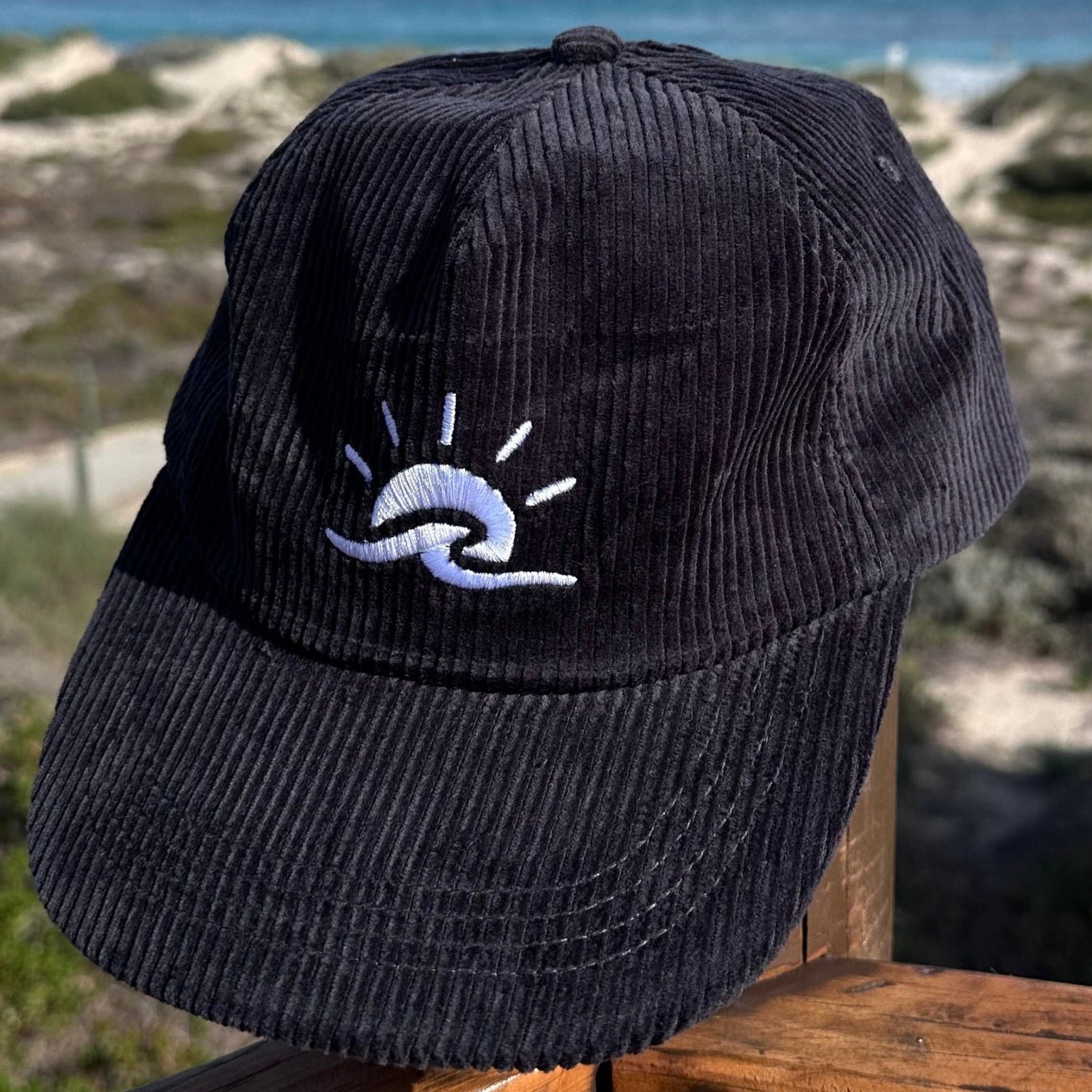 Aquaholics corduroy hat in black, adjustable strap, curved brim, coastal style